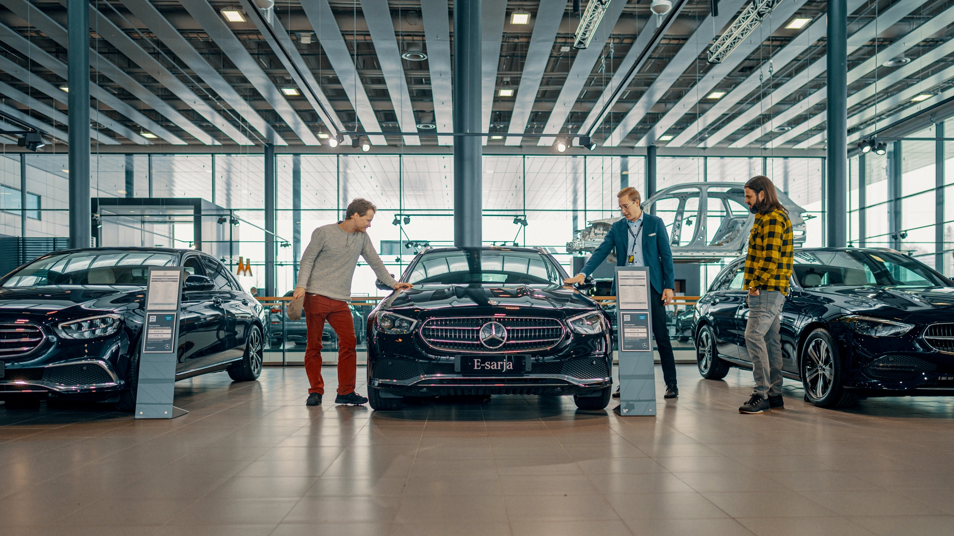 Three men looking at Mercedes-Benz car in a car showroom.