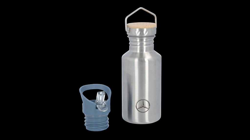 Mustalla taustalla ruostumattomasta teräksestä valmistettu Mercedes-Benz lasten juomapullo. Pullossa bambukorkki ja vieressä muovinen sininen BPA-vapaa sporttikorkki pillillä.
