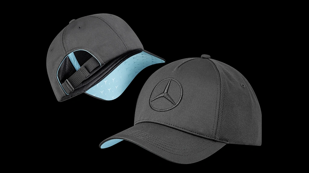 Kaksi Mercedes-Benz-lippalakkia mustalla taustalla - toinen kuvattuna edestä, toinen takaa. Mustassa säädettävässä lippiksessä kohokuvioitu musta tähti otsan kohdalla sekä tähtikuvioitu turkoosi lipan alaosa.